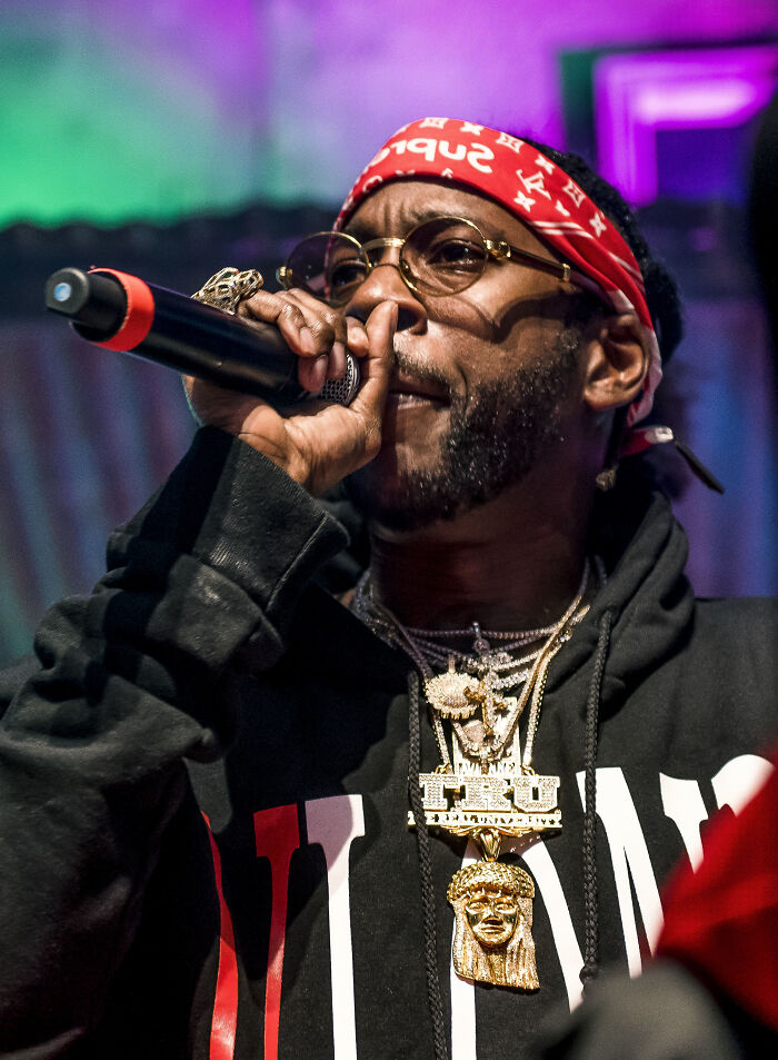 A rapper with a red bandana and many chains, singing into a microphone, representing favorite celebrities.