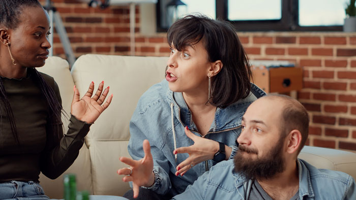 Three friends arguing on a couch, illustrating the conflict after refusing to host Mom's B-Day. Three friends arguing on a couch, illustrating the conflict after refusing to host Mom's B-Day.