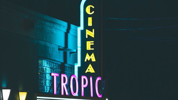 A vibrant neon sign for 'CINEMA TROPIC' at night, unrelated to boyfriend's gift stories.
