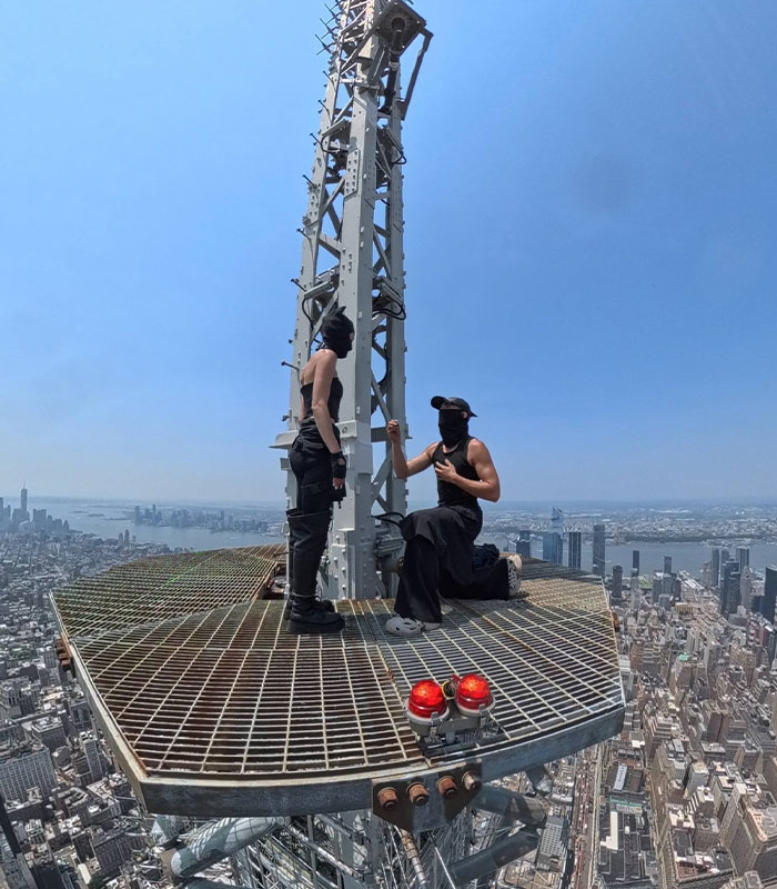One daredevil kneels before another on top of the Empire State Building, leading to their arrest in the daredevil case.