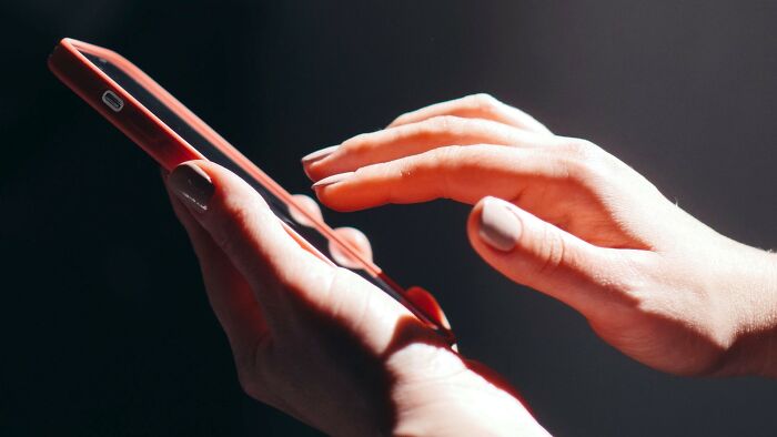 Hands using a smartphone in a dimly lit room, considering life-changing accidents and Am I Overreacting scenarios.