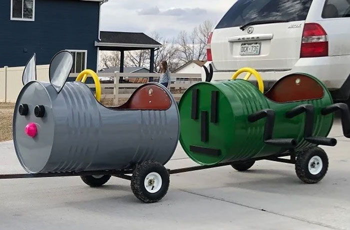 Two barrel-shaped carts, one gray mouse and one green bug, made from old junk for kids to ride, showing creativity.