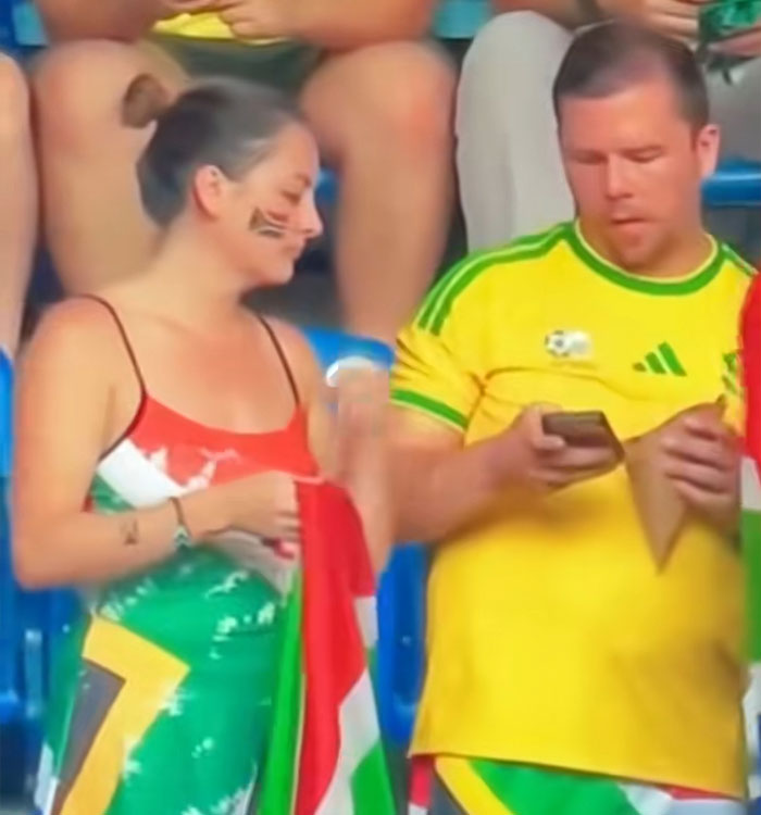 A woman looking at her phone, beside a man engrossed in his, during a viral World Cup moment backfire. A woman looking at her phone, beside a man engrossed in his, during a viral World Cup moment backfire.