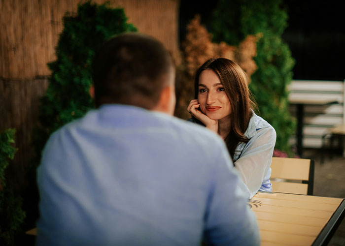 A woman smiling at a man in an outdoor setting. This relates to men and their worst selves.