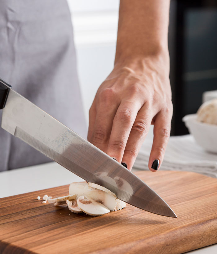 A person slicing mushrooms with a knife. Contact a divorce lawyer for problems besides cheating.