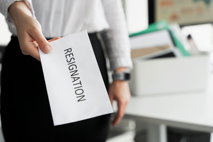 A hand holding a resignation letter, representing an employee ready to quit job after infuriating boss stories.