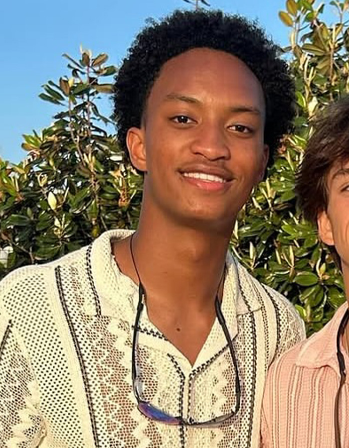 A smiling Nolan Wells in a light-colored patterned shirt, sunglasses hanging from his neck. Nolan Wells case.