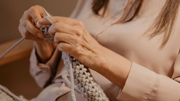 Close-up of a person's hands knitting, focusing on the intricate work, a calm activity amidst family picture disputes.