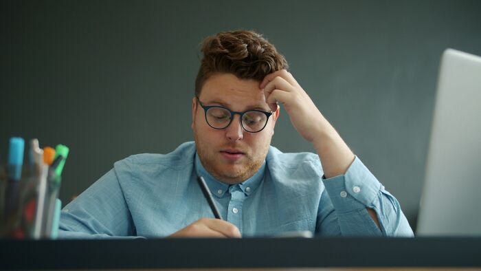 A teacher looking concerned while working at a desk, portraying the grim picture teachers have of Gen Alpha at school.