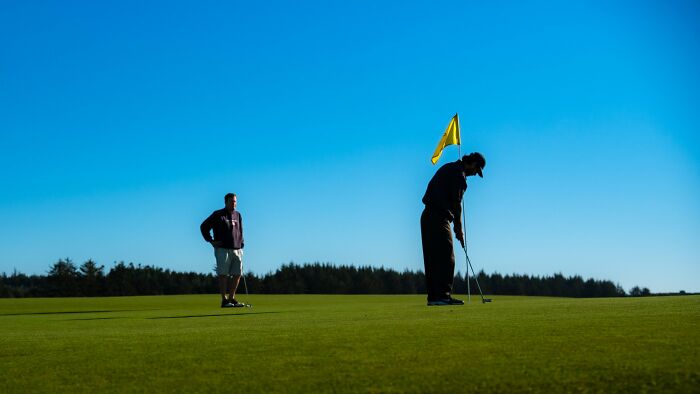 Two men playing golf, one putting and the other watching, an example of stories where people might have overreacted.