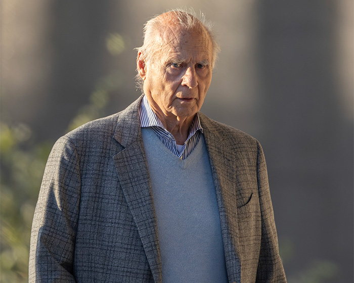 An older reality star in a plaid jacket and light blue sweater, linked to serious crimes.
