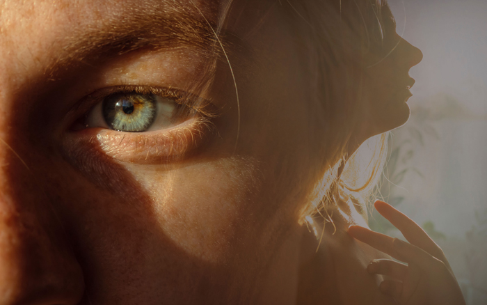 A close-up of a mysterious human eye, with a blurred silhouette of another person in the background, hinting at creepy stories.
