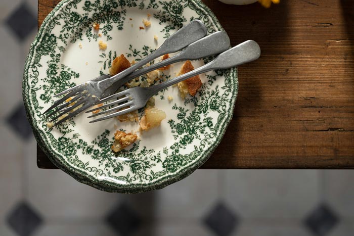 A dirty plate with leftover food and forks, highlighting unhygienic practices.