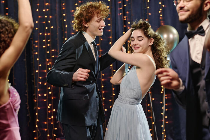 A happy couple dancing at a party with festive lights, enjoying a night out and avoiding any pocket dial stories.