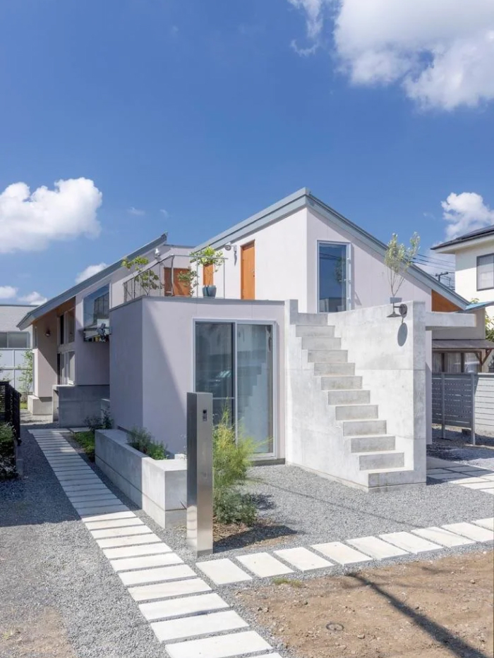 Beautiful modern architecture design with a contemporary home featuring white walls, concrete stairs, and a gravel path.