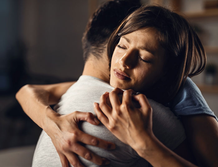 A woman crying while hugging a man, symbolizing the emotional toll of MILs pregnancy competition and miscarries. A woman crying while hugging a man, symbolizing the emotional toll of MILs pregnancy competition and miscarries.
