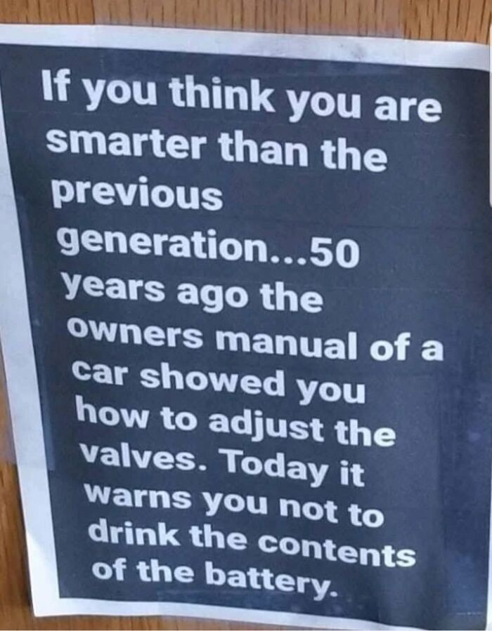 A sign comparing car manuals 50 years ago to today, illustrating Americas cultural decline into idiocy.