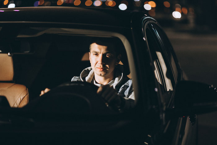 A man driving at night, representing the son who agreed to MIL demands for a four-hour ride before sunrise. A man driving at night, representing the son who agreed to MIL demands for a four-hour ride before sunrise.
