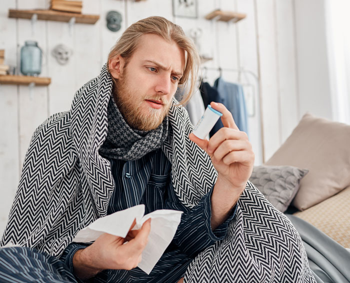 A sick student worker holds medicine and tissue, reflecting on being fired for a sick day.