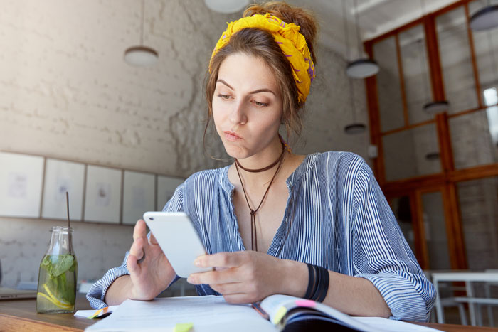A young woman, representing the SIL, looking at her phone, annoyed by the Delulu Mom asking for help.
