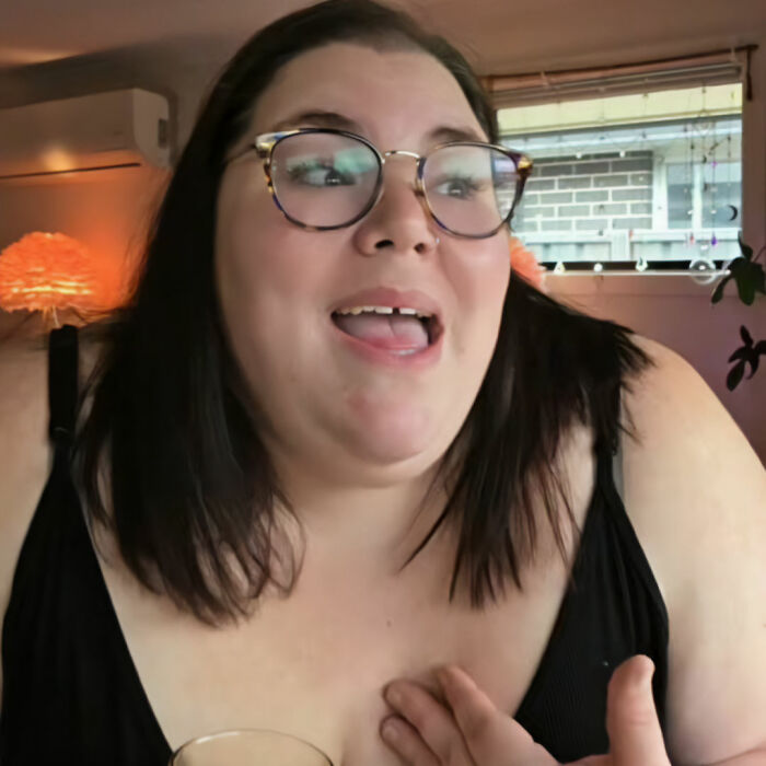 A plus-size influencer in glasses looks surprised, discussing clothing selection. A plus-size influencer in glasses looks surprised, discussing clothing selection.
