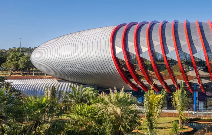 A futuristic, cylindrical building with red-accented panels, an amazing example of modern architecture designs.
