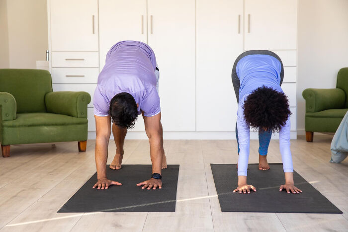 Two people doing a downward dog yoga pose on mats in a bright room. Products, Trends, and Items.
