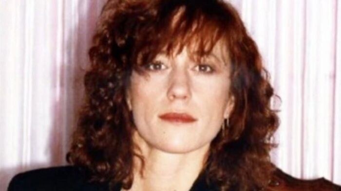 A woman with curly red hair and a serious expression, possibly linked to unsolved mysteries or a mysterious disappearance.