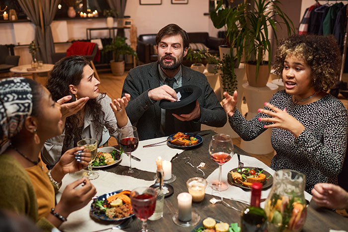 A diverse group of adults at a table discussing, possibly debating, as a 27-year-old refuses to host mom's birthday. A diverse group of adults at a table discussing, possibly debating, as a 27-year-old refuses to host mom's birthday.