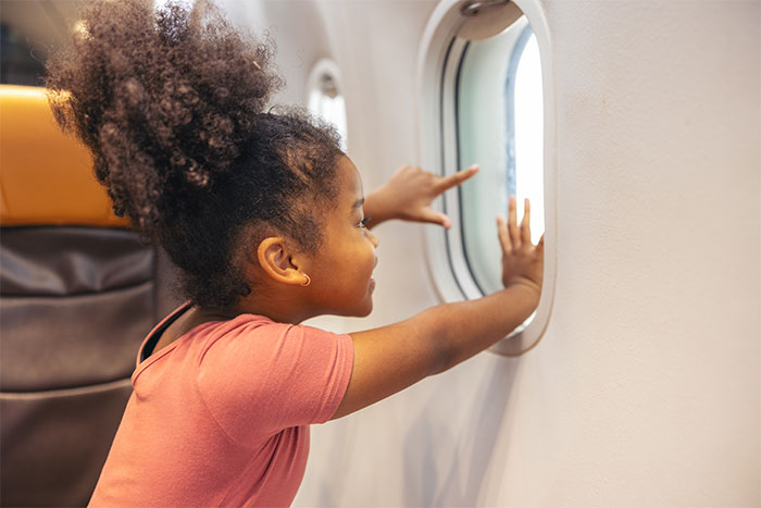 A happy child looks out of a window seat on a flight. A happy child looks out of a window seat on a flight.