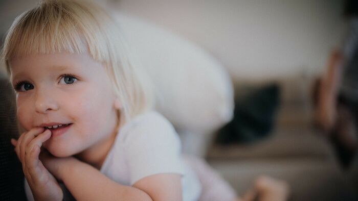 A smiling child with blonde hair, innocent and unaware of being in the wrong for a boyfriend's gift.
