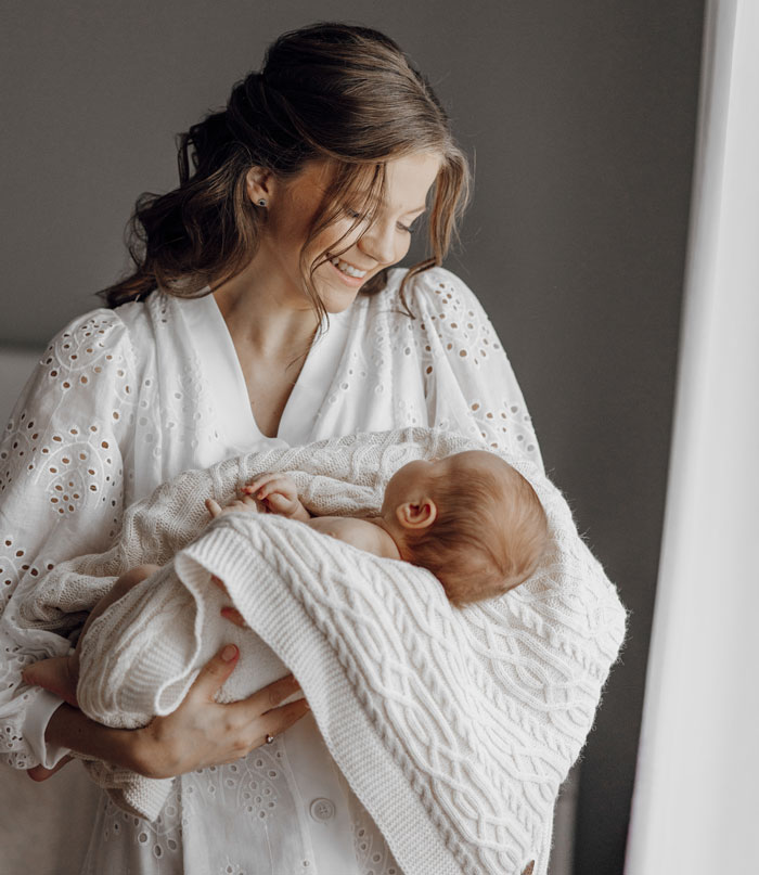 A smiling mother holding her newborn baby, symbolizing the bond despite men who walked out after having a baby.