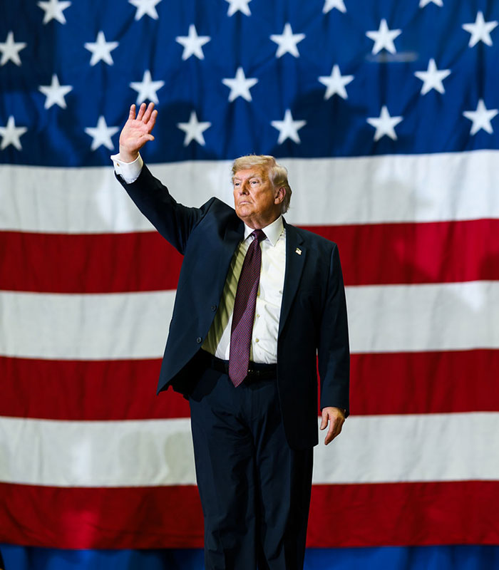 Trump with hand raised, standing in front of an American flag, from the unhinged video. Trump with hand raised, standing in front of an American flag, from the unhinged video.