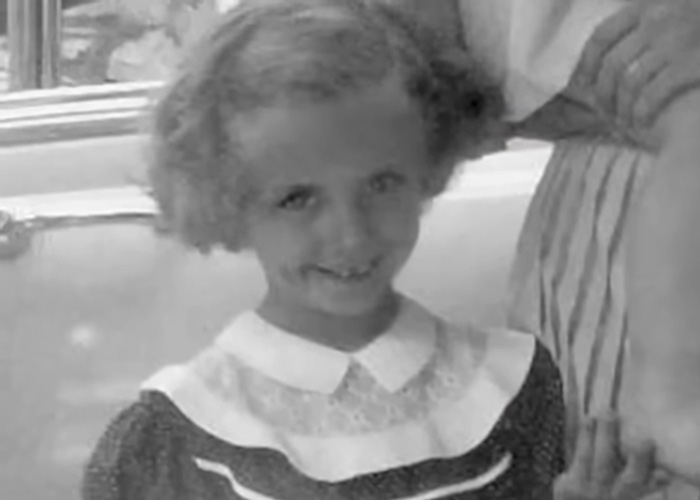 A young polio survivor, a girl, smiling in a black and white photograph.
