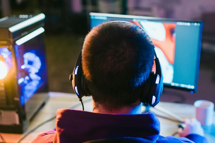 A person wearing headphones and gaming at a computer, depicting why people got fired from their jobs.