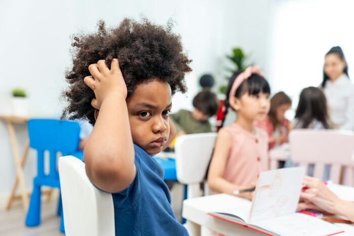 A Gen Alpha child with a thoughtful expression in a classroom, highlighting Gen Alpha's school performance.