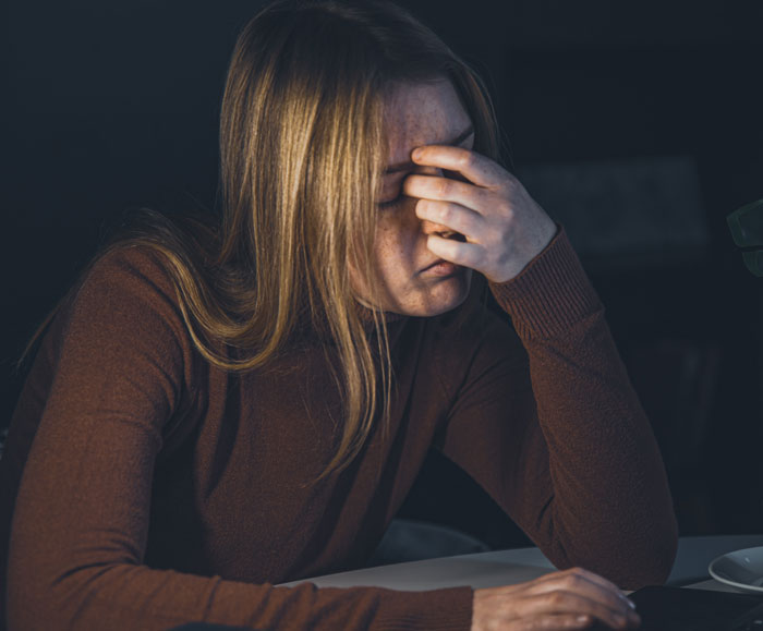 A distressed woman holding her head, reflecting on hard truths that women learned.