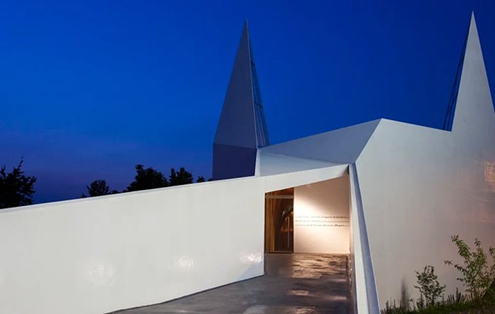 Striking white modern architecture designs with sharp angles under a deep blue evening sky.