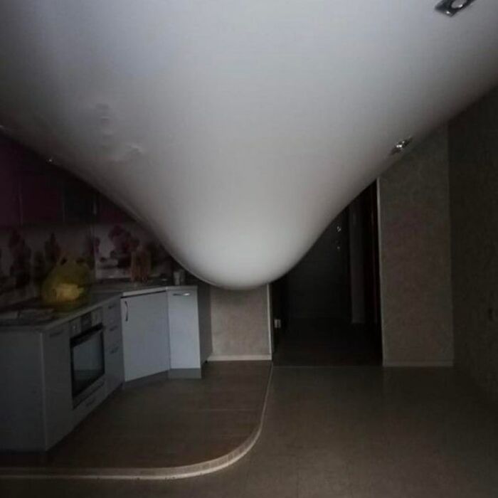 A kitchen with a severely sagging ceiling, creating a confusing image that needs a priest.