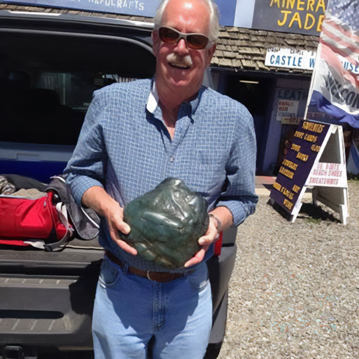 A man proudly holds a mysterious discovery, a large dark rock, reflecting an ancient American history. A man proudly holds a mysterious discovery, a large dark rock, reflecting an ancient American history.