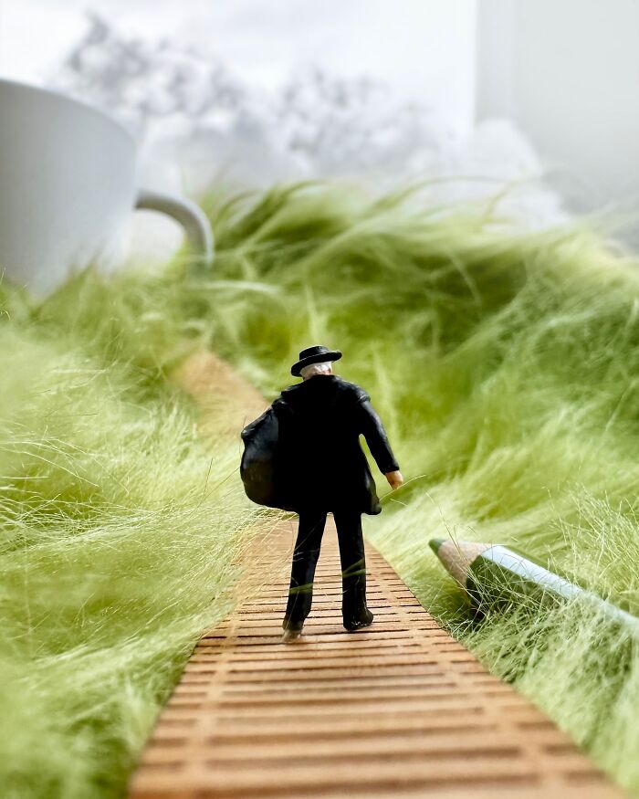 Artist Derrick Lin turns his office desk into intricate diorama sets, featuring a figure walking on a path through green fuzz.