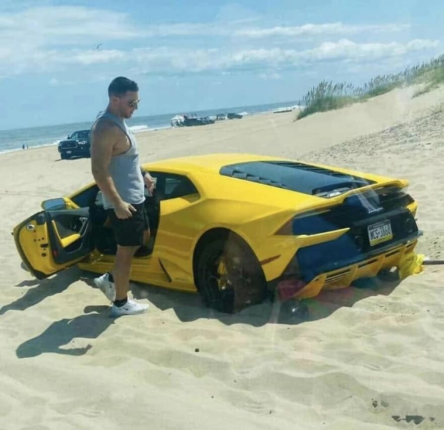 A yellow Lamborghini sports car stuck in sand at the beach, showing a rough day behind the wheel.