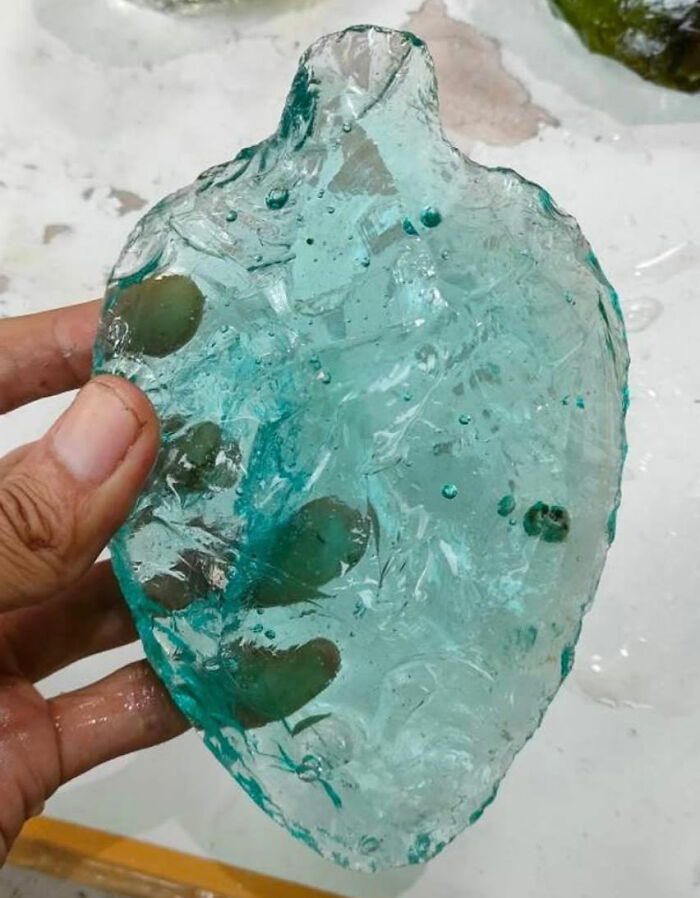 A hand holds a translucent, light blue, rough-edged object, a mysterious discovery from ancient American history. A hand holds a translucent, light blue, rough-edged object, a mysterious discovery from ancient American history.