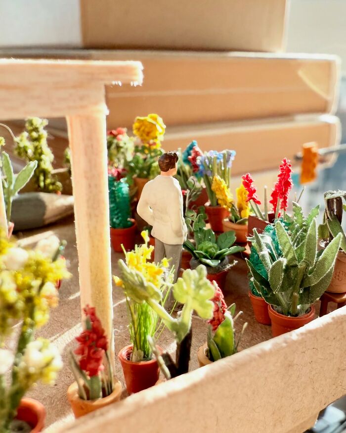 Derrick Lin's intricate diorama set on an office desk showcases a figure among numerous potted miniature plants and flowers.