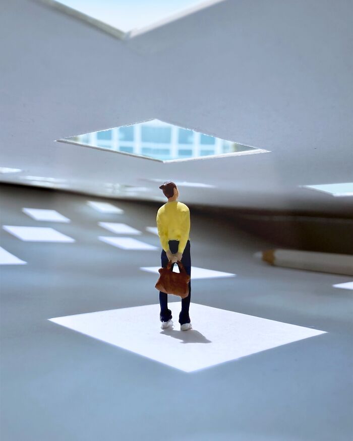 Artist Derrick Lin turns his office desk into intricate diorama sets, with a person standing under a skylight.