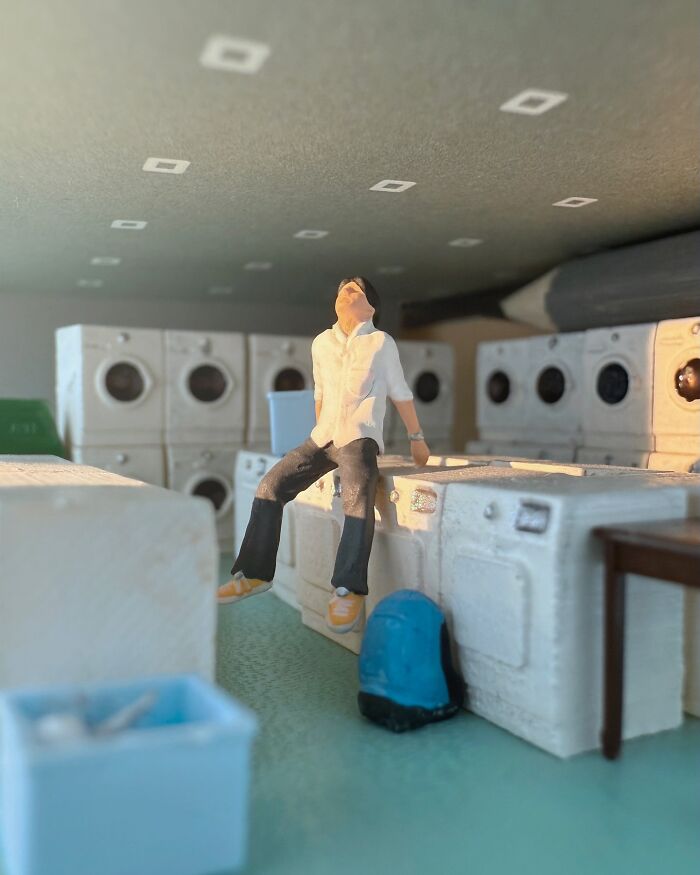 Artist Derrick Lin turns his office desk into intricate diorama sets, showing a man resting in a laundromat.