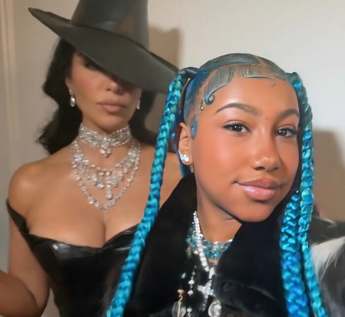 Woman with turquoise braids posing with another woman in black hat and jewelry