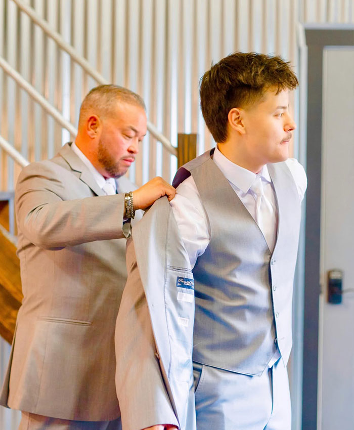 A man helps Collin Gosselin adjust his gray suit, highlighting the public battle surrounding Collin Gosselin.