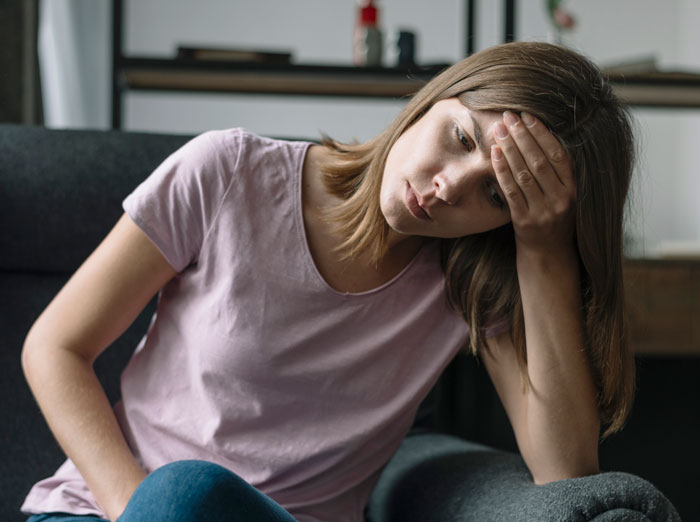 A frustrated woman with her hand on her forehead, grappling with the backfire of travel plans.