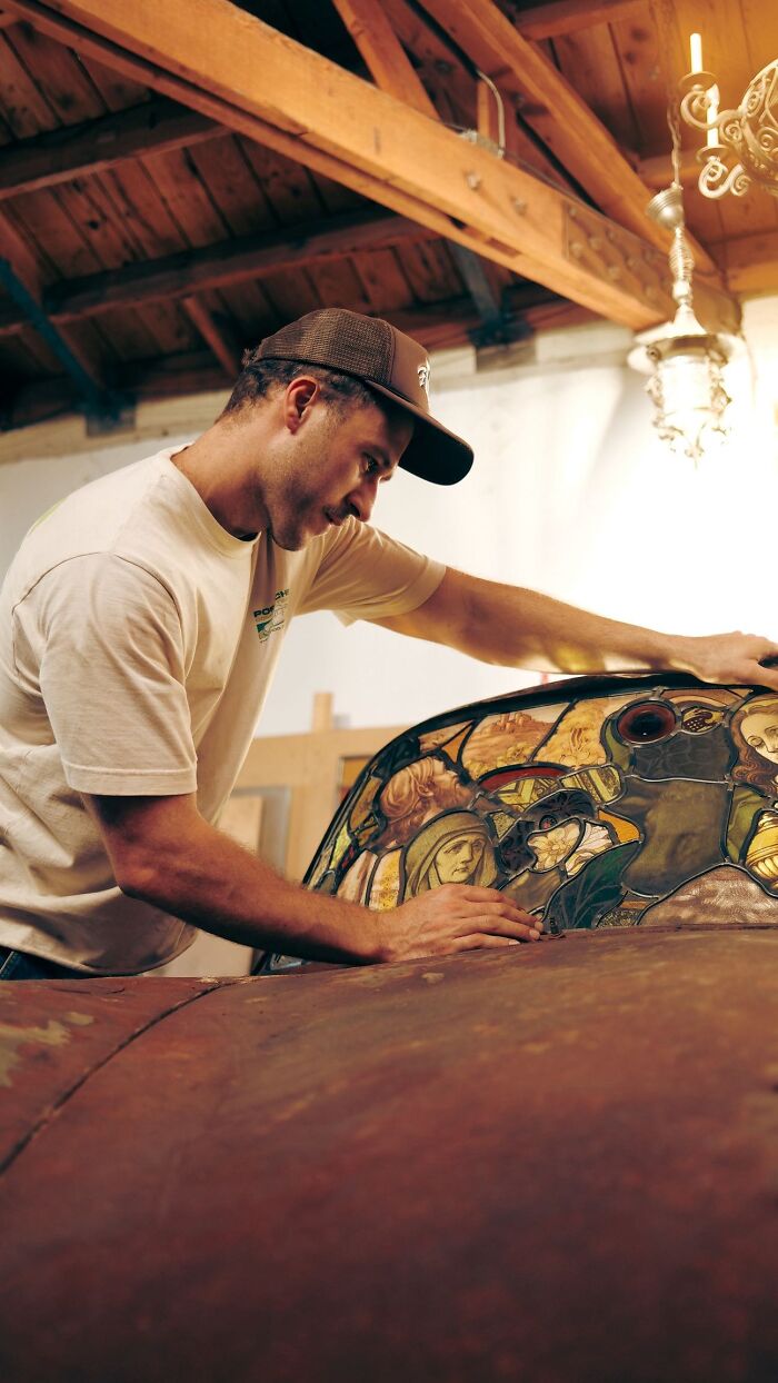 Artist creating a stained-glass sculpture from a burned, rusted Porsche 911, showcasing artistic transformation.